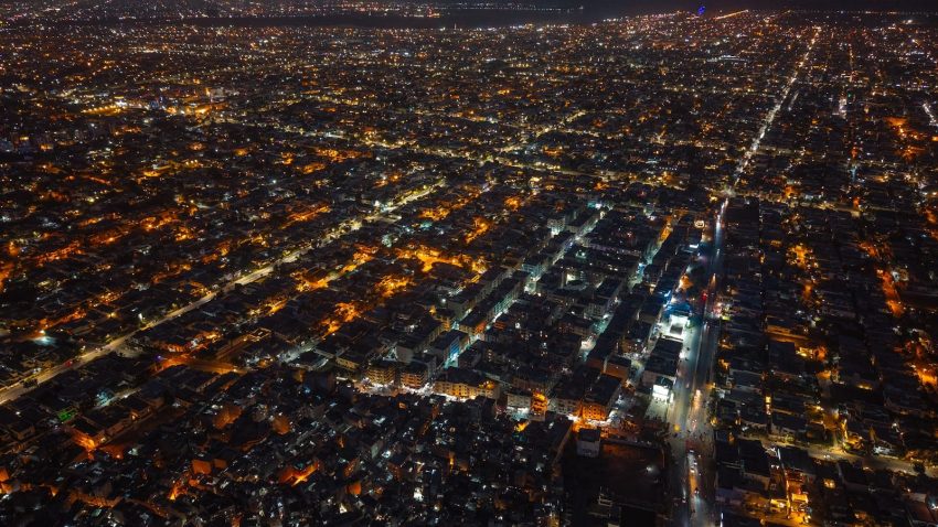 Aerial view of a city at night with glowing lights.